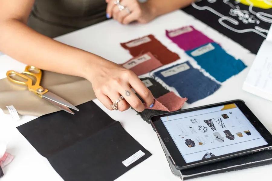 A designer comparing fabric swatches with product sketches on a tablet