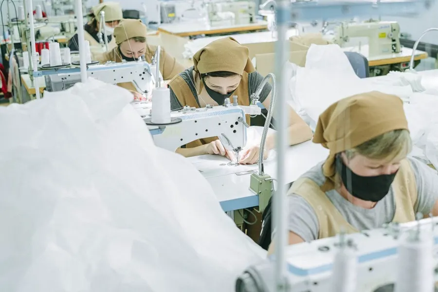 Workers at sewing machines on a factory line