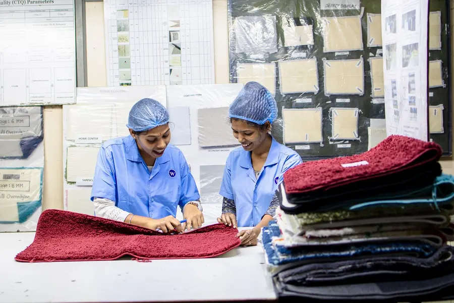 Two workers inspecting fabric at a quality control table